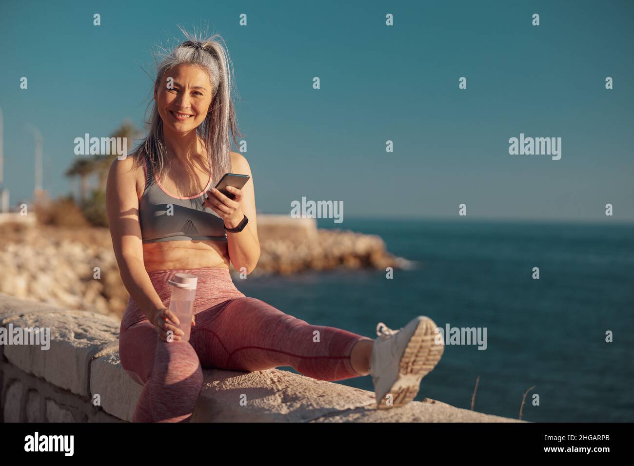 Erwachsene Frau, die sich nach dem Training am Wasser ausruhte Stockfoto