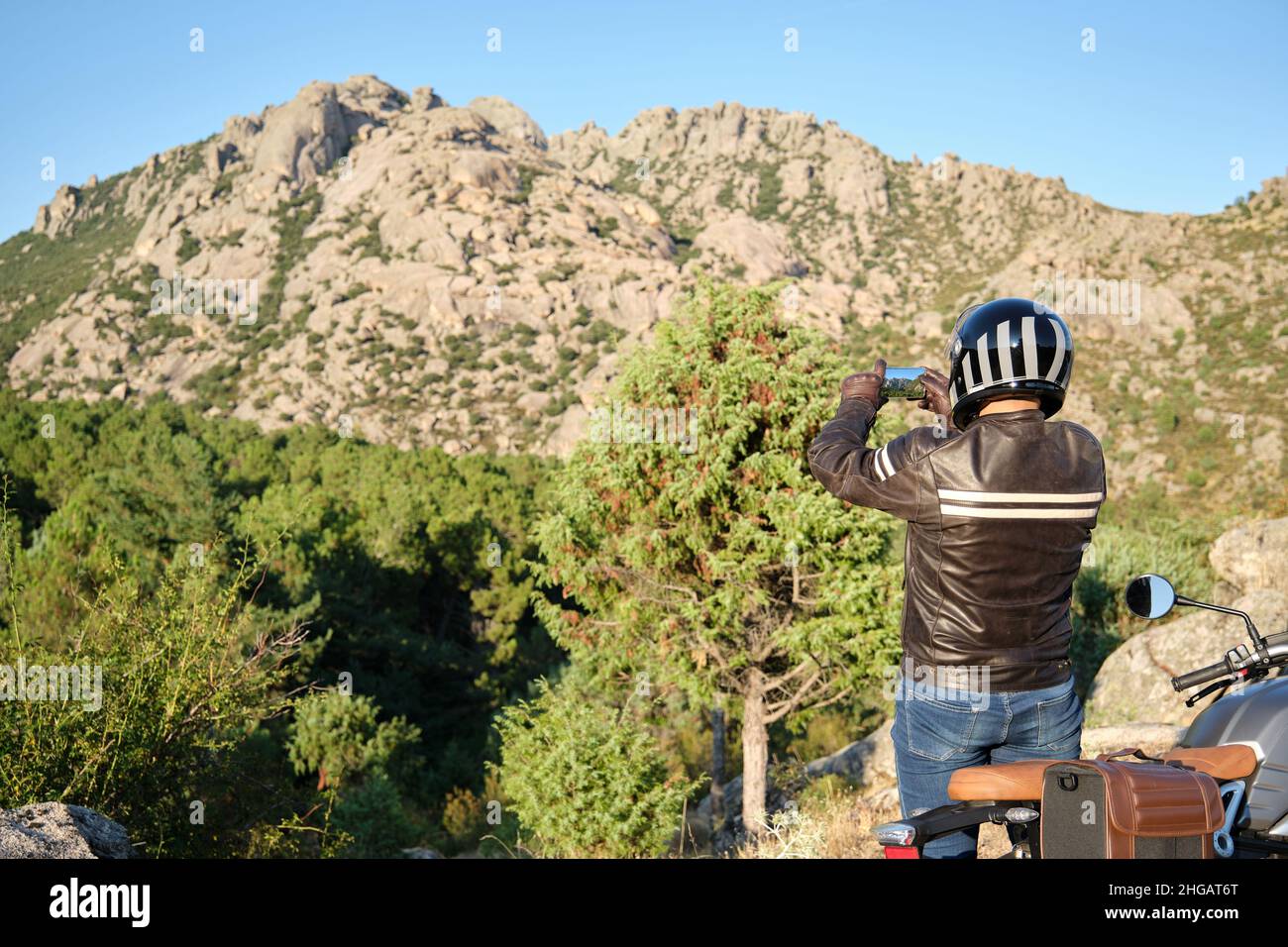 Ein Mann auf einem Motorrad, der in der Natur ein Foto mit einem Smartphone gemacht hat. Stockfoto