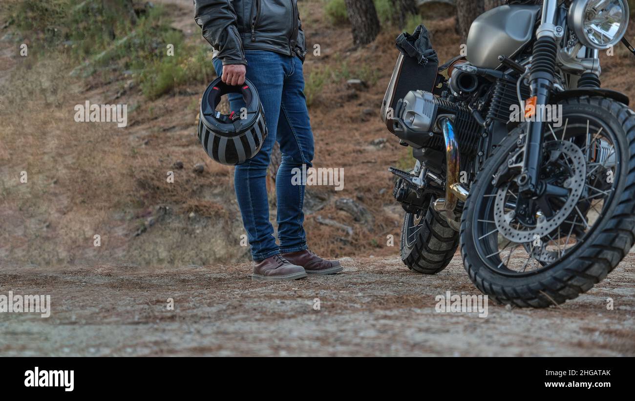 Nicht erkennbare Person mit Helm in der Hand, die neben dem geparkten Motorrad steht Stockfoto