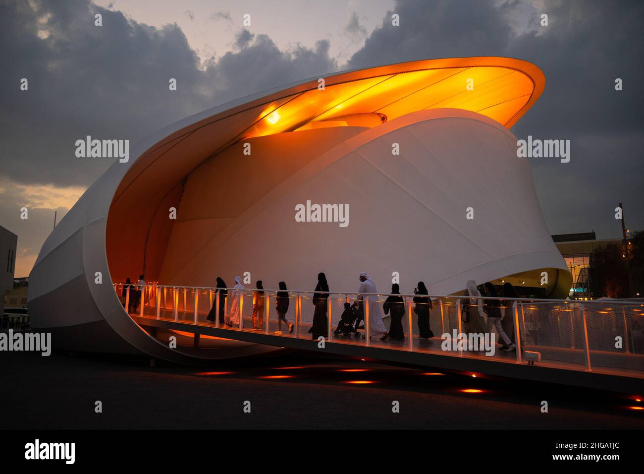 Futuristischer, schnecke geformter luxemburgischer Pavillon während des Sonnenuntergangs mit islamistischen Menschen, die auf der Dubai Expo 2020 nach innen gehen Stockfoto