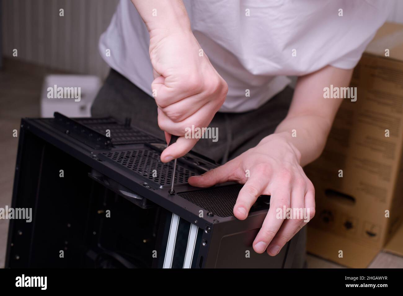 Ein Mann zu Hause sammelt, zerlegt einen Computer. Hände eines Mannes halten Drähte, verbindet Drähte. Sammeln eines Computers für Profis, ein Gaming-Computer Stockfoto