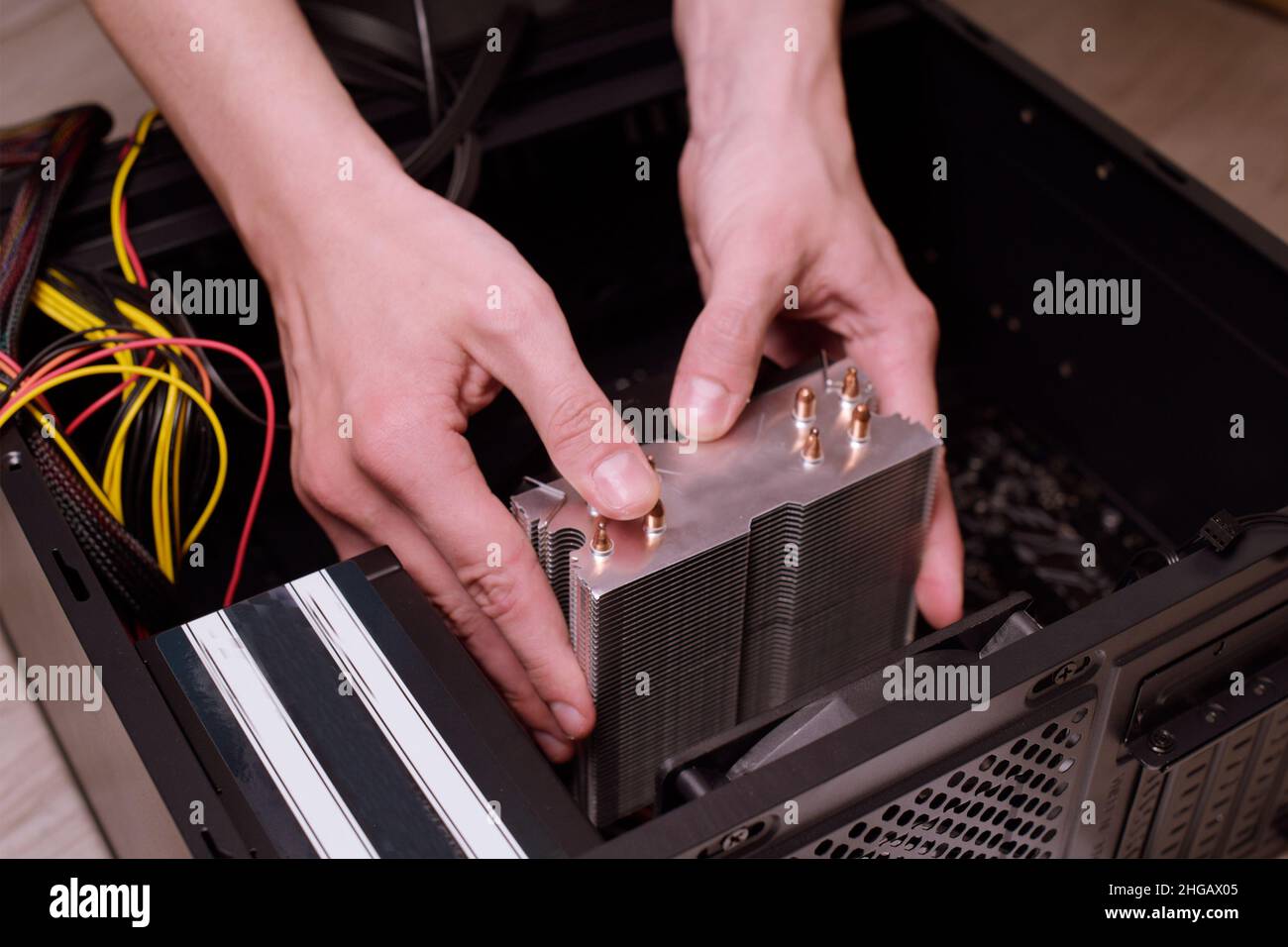 Ein Mann zu Hause sammelt, zerlegt einen Computer. Hände eines Mannes halten Drähte, verbindet Drähte. Sammeln eines Computers für Profis, ein Gaming-Computer Stockfoto