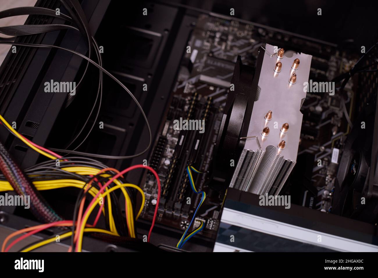 Ein Mann zu Hause sammelt, zerlegt einen Computer. Hände eines Mannes halten Drähte, verbindet Drähte. Sammeln eines Computers für Profis, ein Gaming-Computer Stockfoto