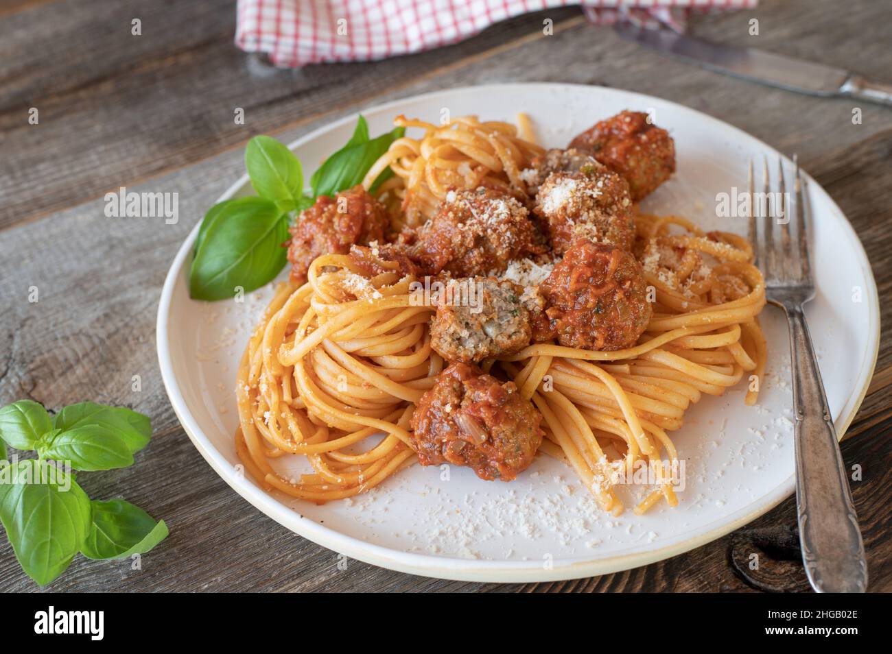 Traditionelles italienisches Gericht mit Spaghetti und Fleischbällchen. Serviert mit einer köstlichen Tomatensauce auf einem Teller auf einem Holztisch Stockfoto