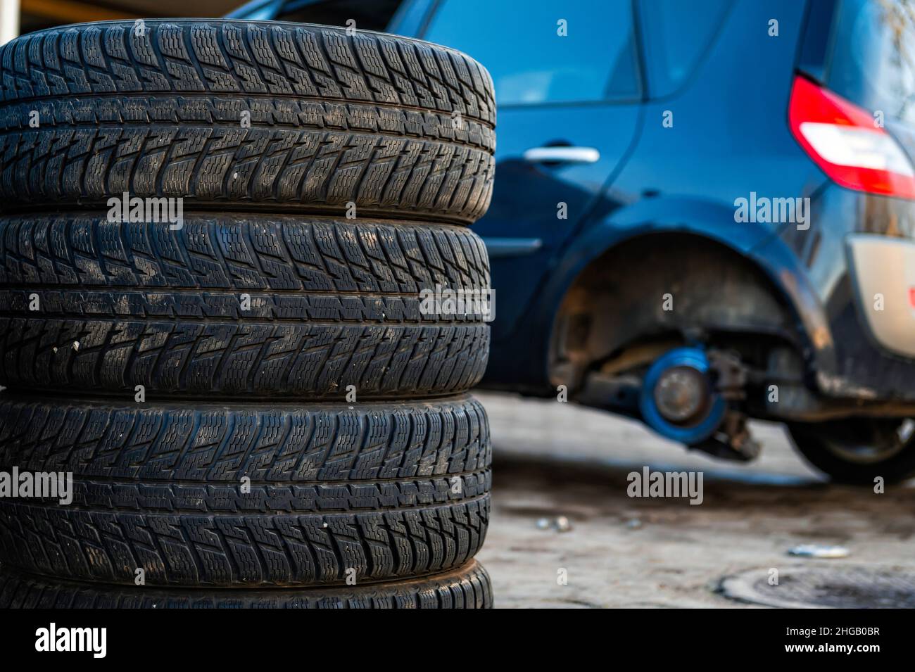 Winterreifen neben dem Auto im Radservice, saisonales Reifenwechselkonzept, Nahaufnahme Stockfoto