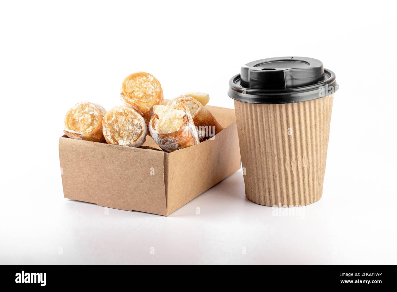 Kaffee-Tasse aus Kraftpapier und Schachtel mit kleinen süßen Kuchen auf weißem Hintergrund isoliert. Konzept der „Take Away“-Lieferung. Teil des Sets. Stockfoto