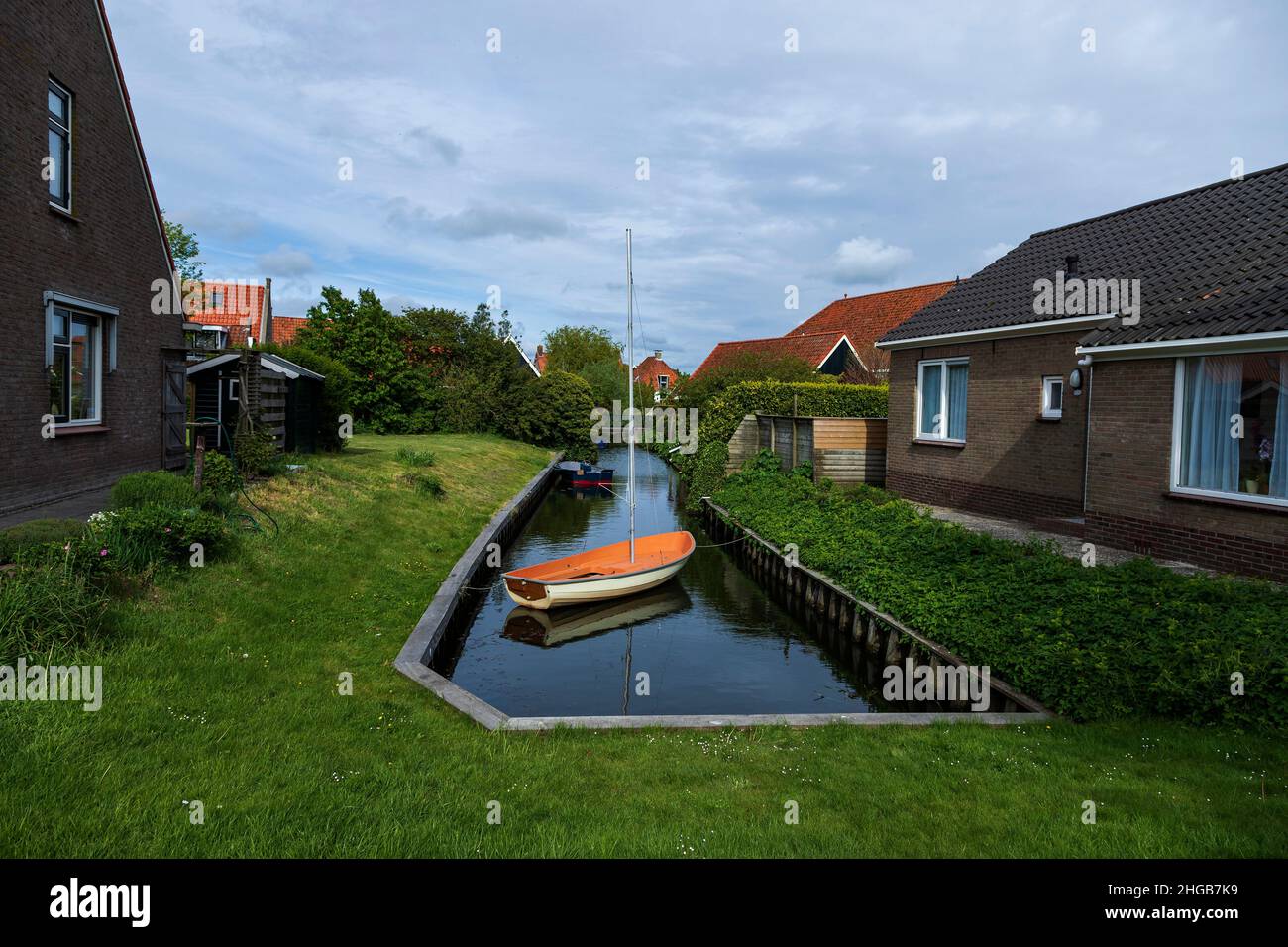 Wasserkanal zwischen Häusern in Hindeloopen in Holland. Es gibt ein Boot auf dem Wasser. Stockfoto