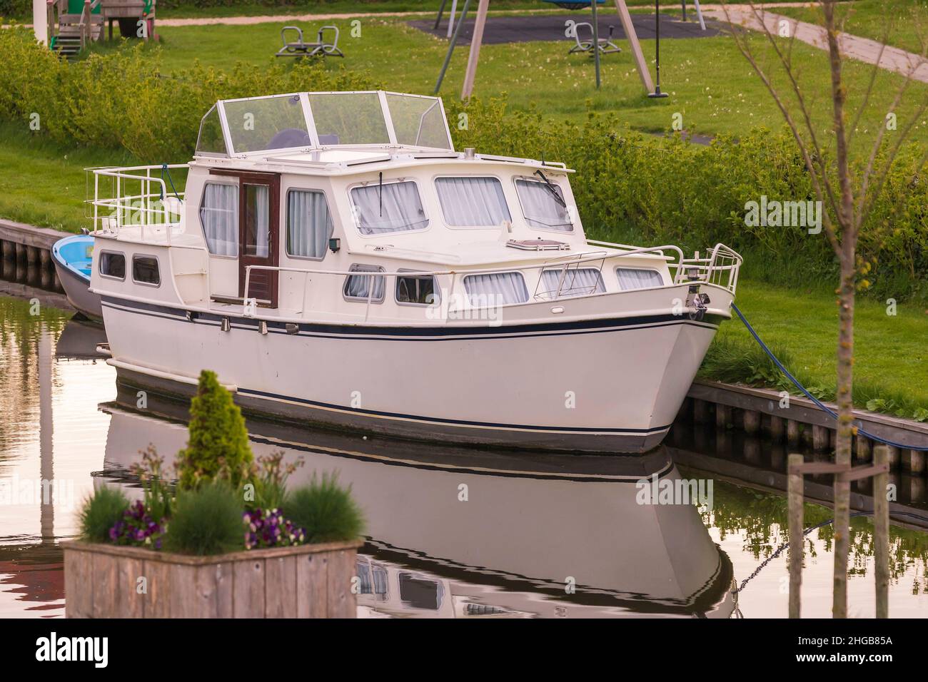Boot - Hausbot auf einem Kanal in Hindeloopen, Holland. Das Schiff wird im Wasser reflektiert. Stockfoto