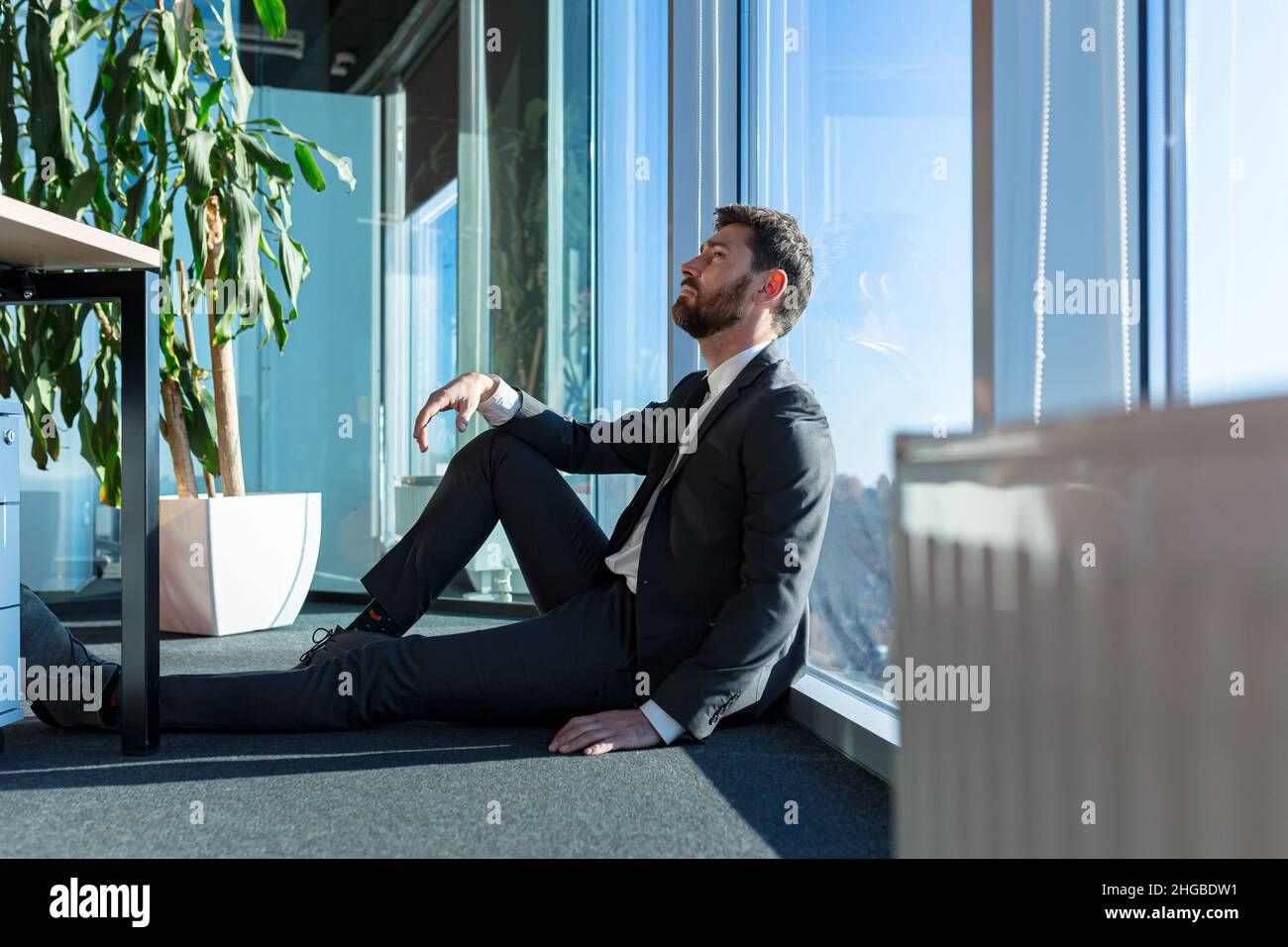 Deprimierter Mann, der auf der Büroetage saß, der Angestellte war enttäuscht und gefeuert Stockfoto
