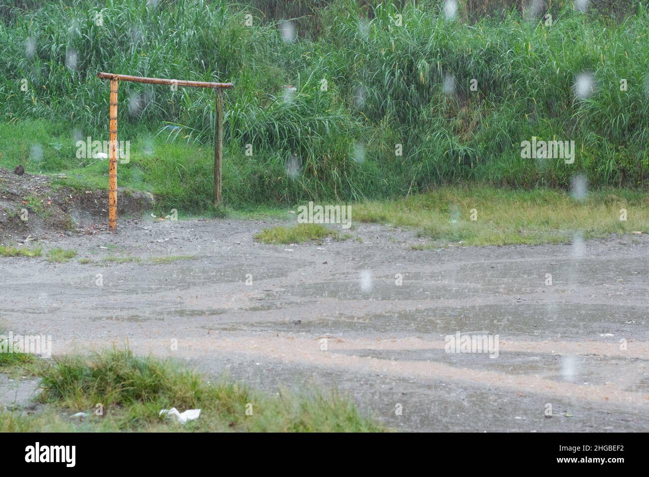 Fußballplatz in armer kolumbianischer Nachbarschaft. Fußballplatz mit Bambuszielen und schmutzigen Spielfeld. Regenwasser fällt in einem armen Nachbarn auf das Feld Stockfoto