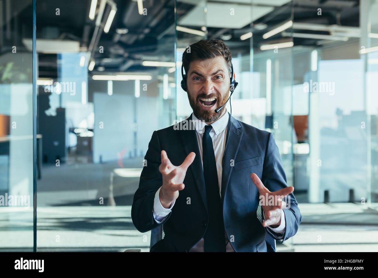 Wütender Callcenter-Mitarbeiter, Blick auf die Kamera und Schreien vor Wut, Mann mit Headset, der technischen Support und Videoanruf abgibt Stockfoto