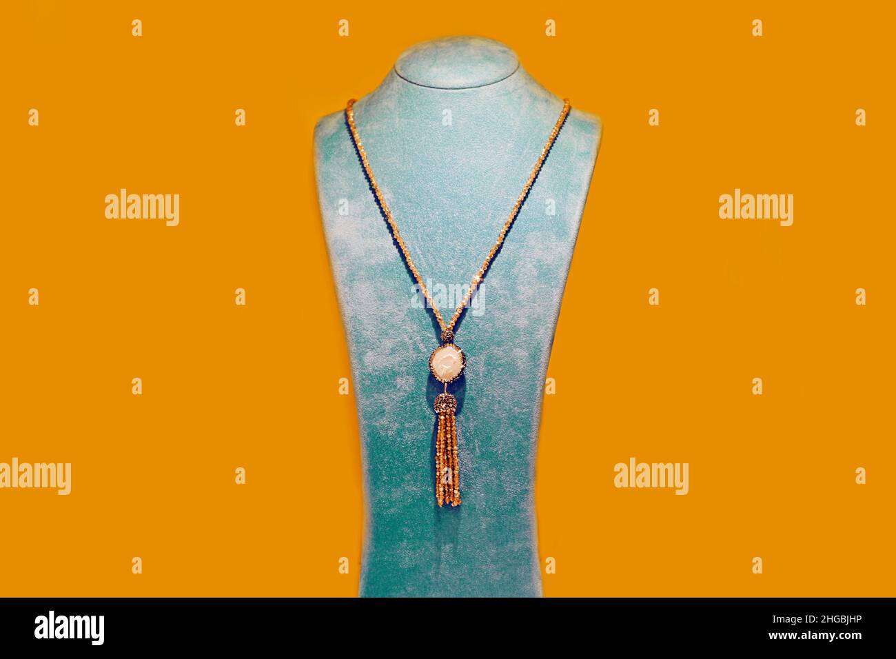 Schöne Schmuckstücke. Halskette auf gelbem Anker-Hintergrund. Schmuck auf blauem Ständer. Stockfoto