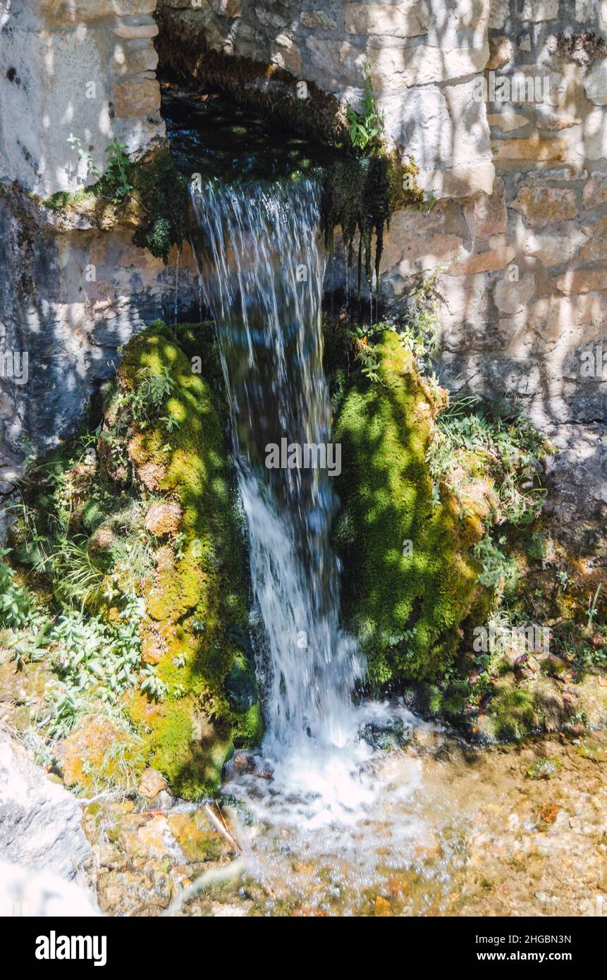 Vertikales Foto eines kleinen Wasserfalls des Flusses Gromejón in Caleruega in einem Loch in der Wand, Burgos, Castilla y León, Spanien. Stockfoto