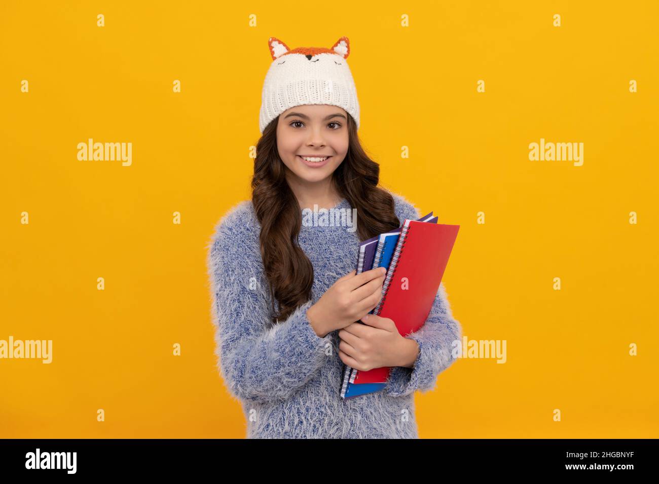 ausdruck positiver Emotion. Wintermode. Positives Kind mit lockigen Haaren im Hut. Zurück zur Schule. Stockfoto