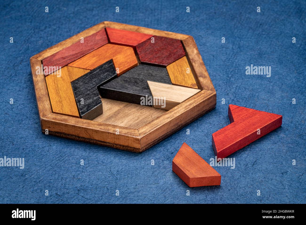 Holzhexagon Tangram Puzzle gegen strukturierte handgemachte Rindenpapier, Gehirn Teaser und lustiges Spiel mit mehreren Möglichkeiten zu lösen Stockfoto