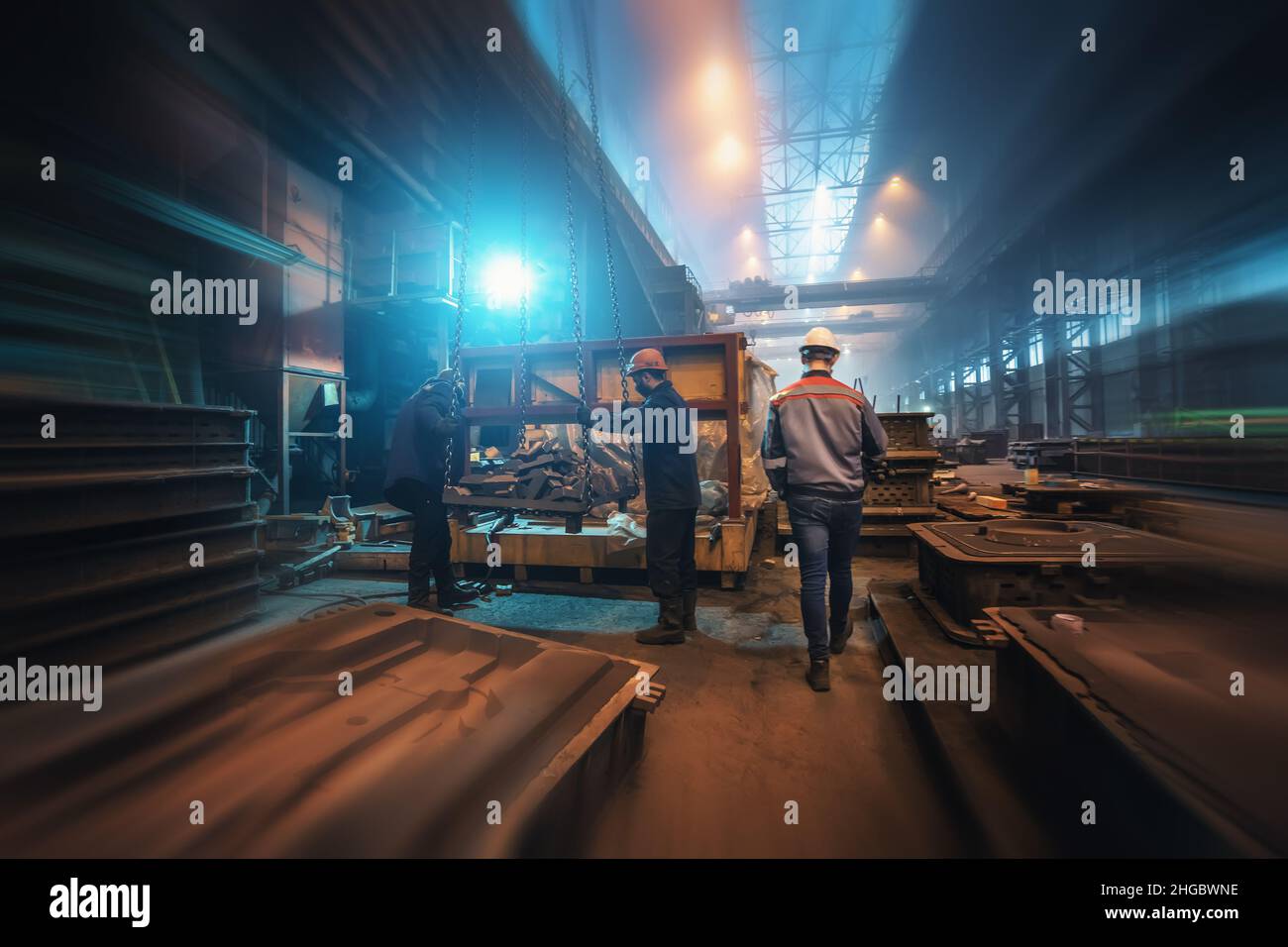Arbeiter in einer modernen Metallwerkstatt. Innenraum der Gießerei. Produktionslinie für die Schwerindustrie. Bewegungsunschärfe. Stockfoto