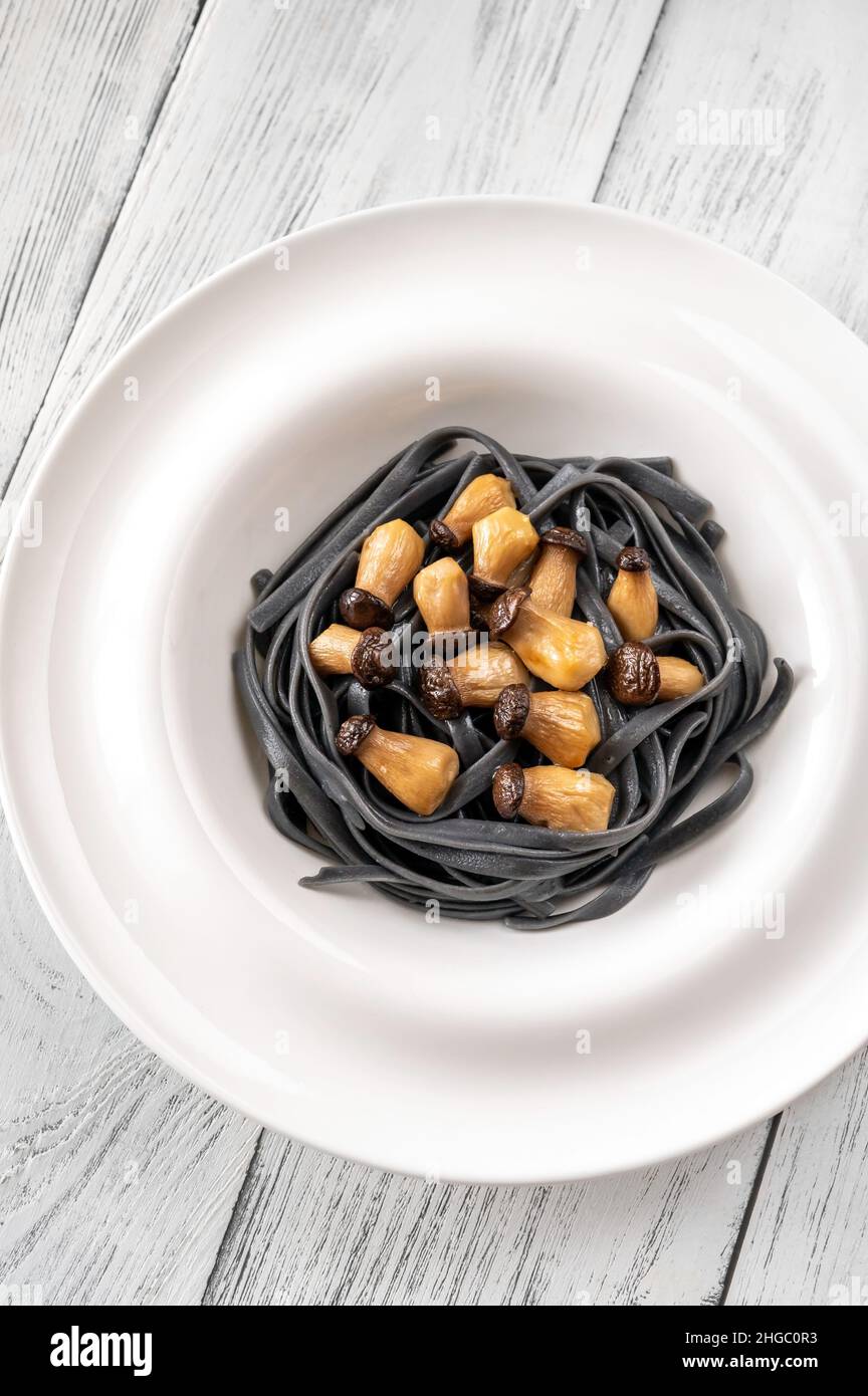 Tintenfisch Tinte Linguine Pasta mit Babypilzen Stockfoto