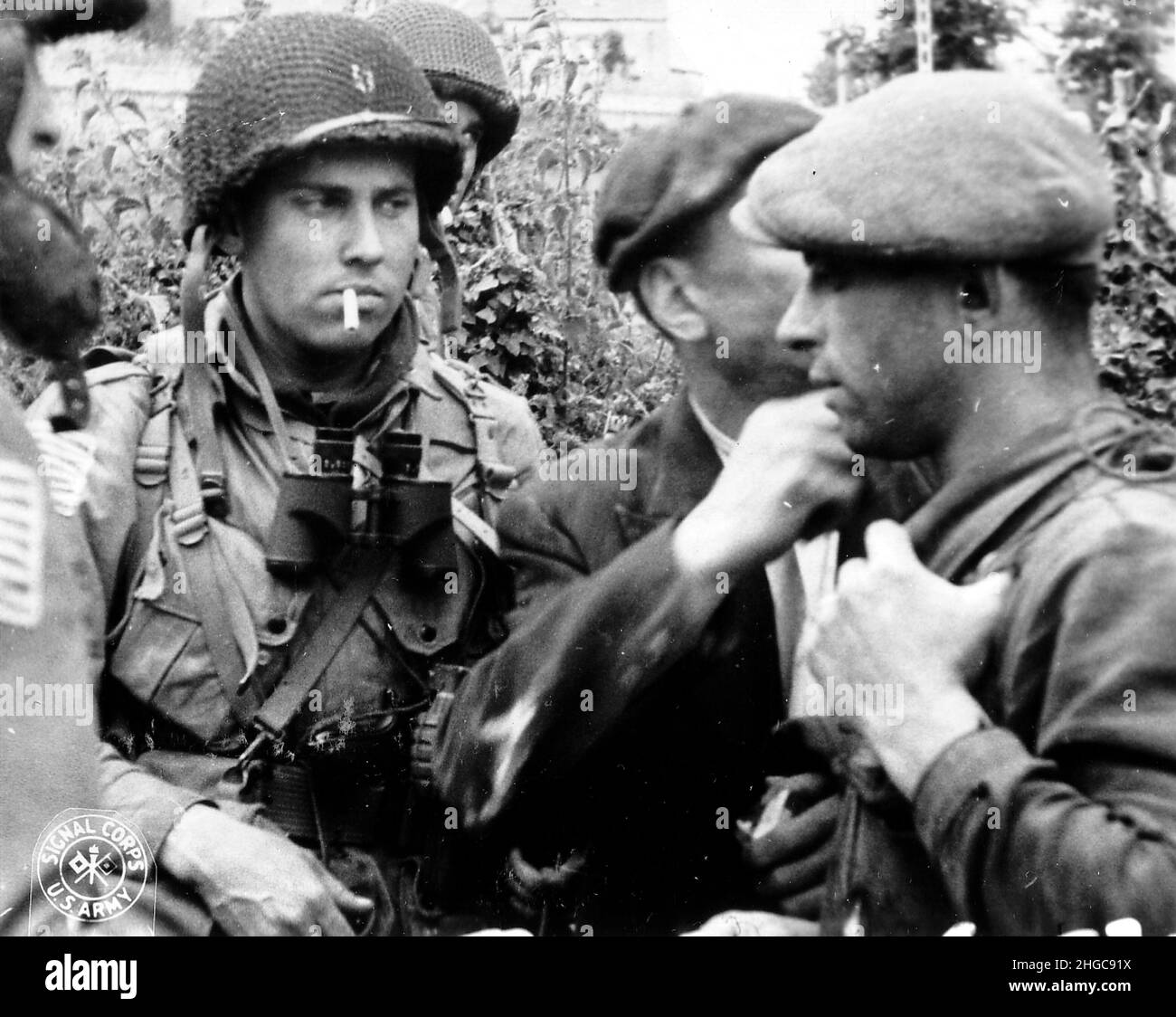 Mitglieder des französischen Widerstands und der US 82nd Airborne Division diskutieren die Situation während der Schlacht in der Normandie im Jahr 1944. Stockfoto