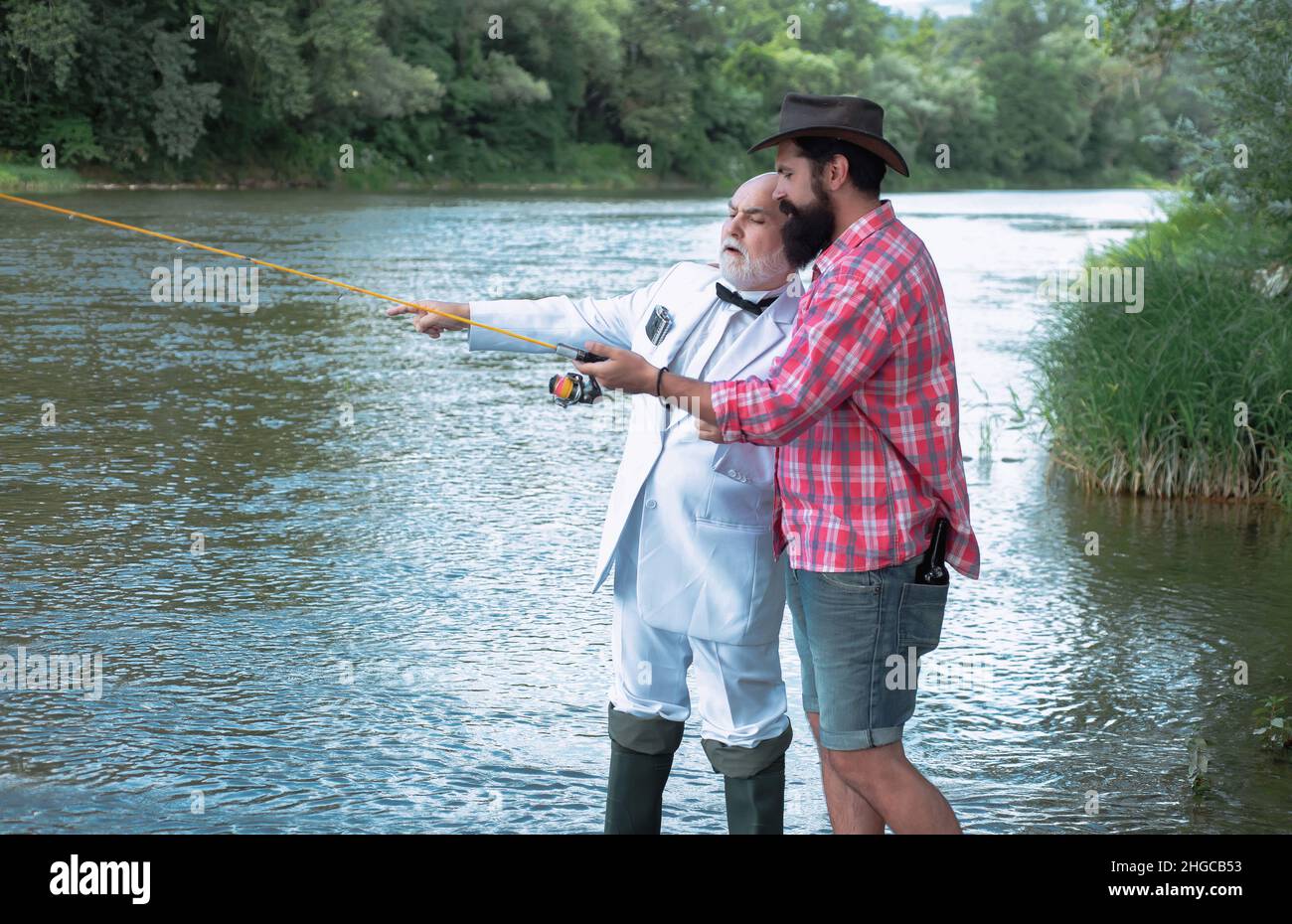 Vater mit Sohn auf dem Fluss genießen Angeln halten Angelruten. Angeln. Fischer mit Angelrute am Fluss. Glückliches Familienkonzept - Vater Stockfoto