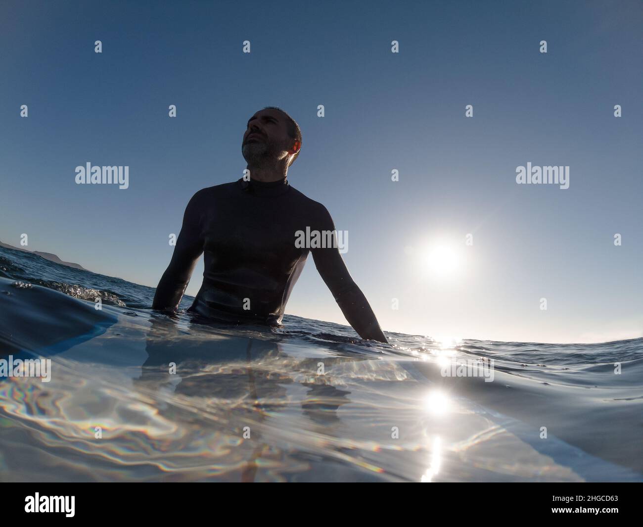 Kaukasischer Surfer sitzt auf seinem Surfbrett im Wasser und wartet auf Wellen Stockfoto