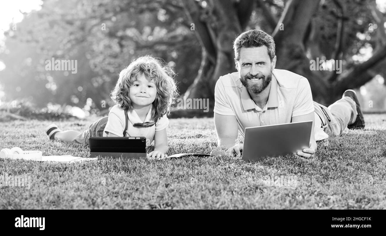 Lernen im Freien. Vater und Sohn spielen oder studieren mit dem Laptop im Park. Stockfoto