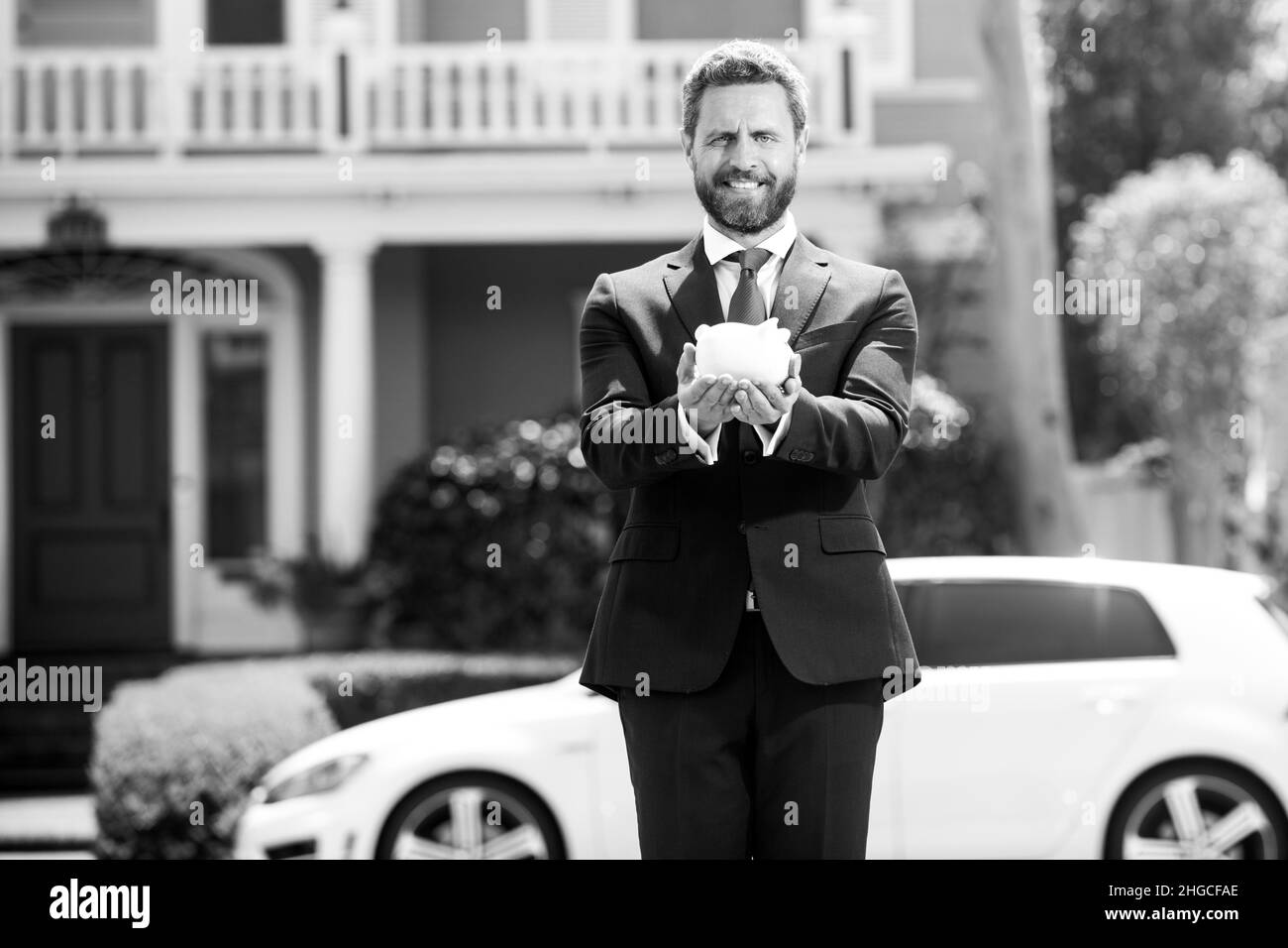 Mann spart Geld. Geschäftsmann, der eine Münzbank hält. Konzept für Finanzeinsparungen, finanzieller Erfolg. Stockfoto