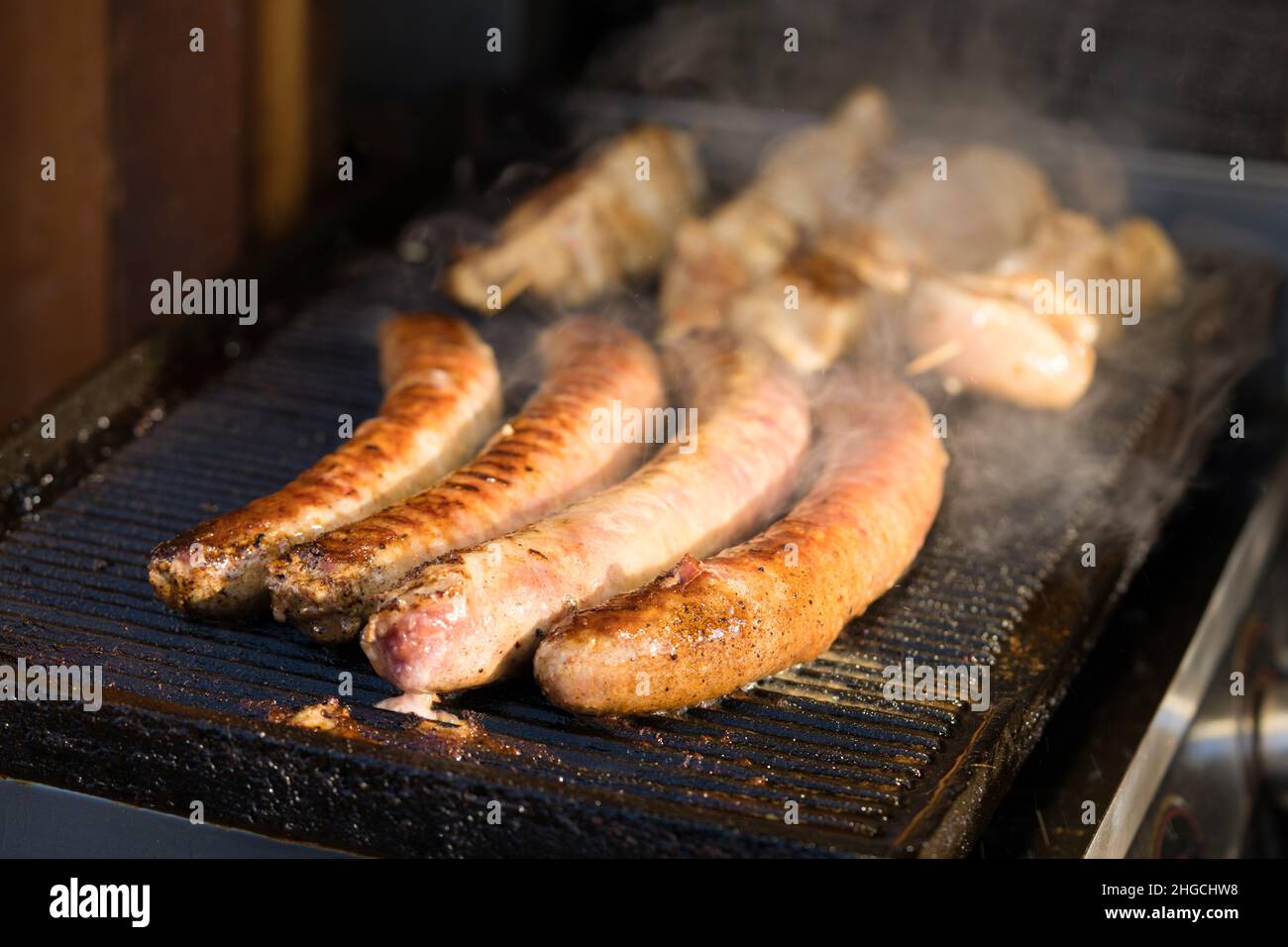 Nahaufnahme von köstlichen gegrillten und gebratenen Würstchen. Street Food auf dem lokalen Markt des traditionellen Festivals. Lebensmittelhändler auf der Straße Stockfoto