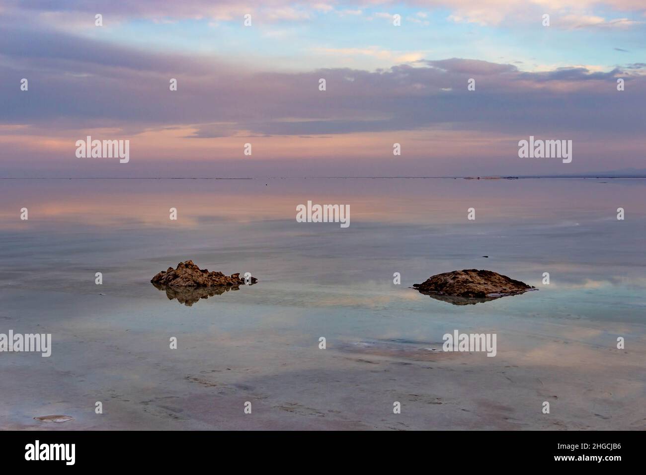 Zwei Felsen im See und ein violetter Sonnenuntergang Stockfoto