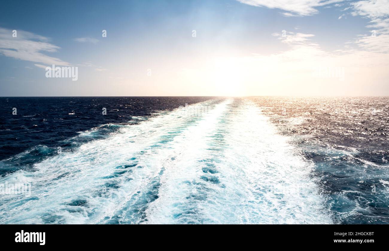 Trail im Meer von ​​a Segelkreuzfahrtschiff, das bei Sonnenuntergang wegsegelt. Stockfoto
