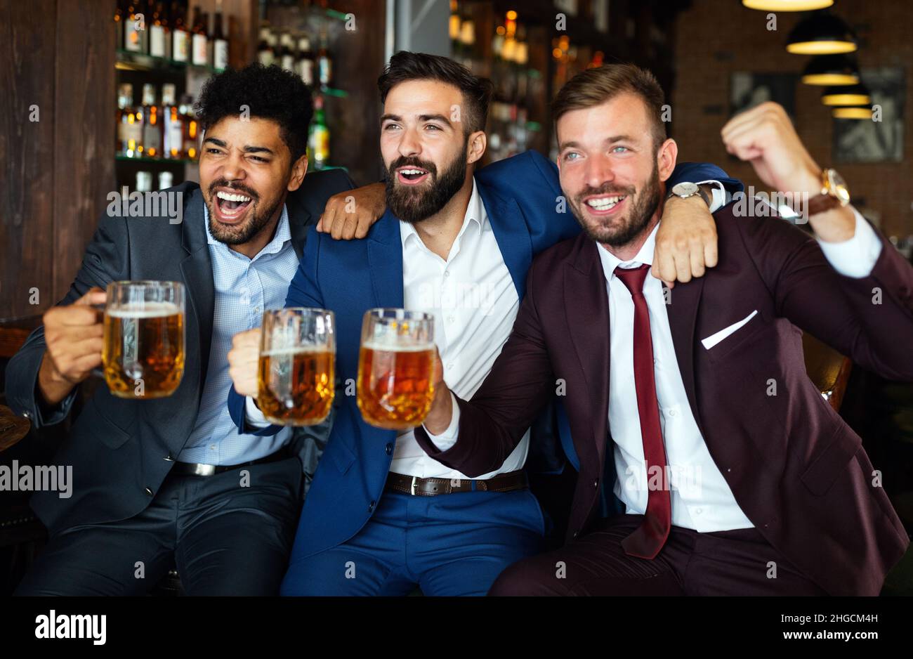 Männerfans schreien und beobachten Fußball im Fernsehen und trinken Bier in einer Kneipe Stockfoto