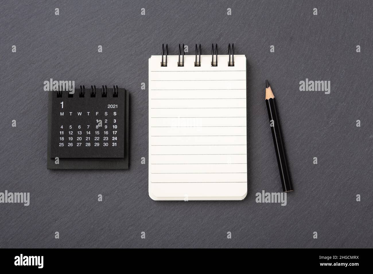 Kalender mit Notizbuch auf schwarzem Steingrund, Draufsicht Stockfoto