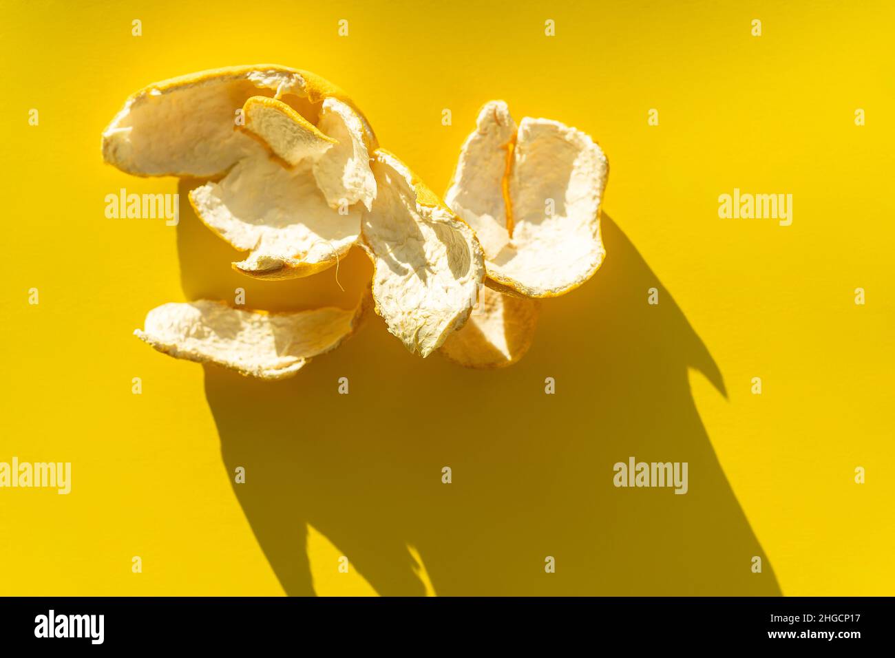 Orangenschale auf gelbem Hintergrund in hellem Licht. Stockfoto