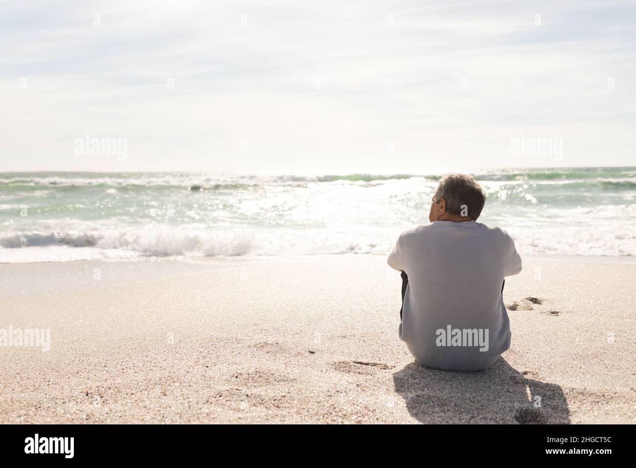 Rückansicht eines älteren Biracial-Mannes, der an sonnigen Tagen vom Strand aus den Horizont über dem Meer blickt Stockfoto