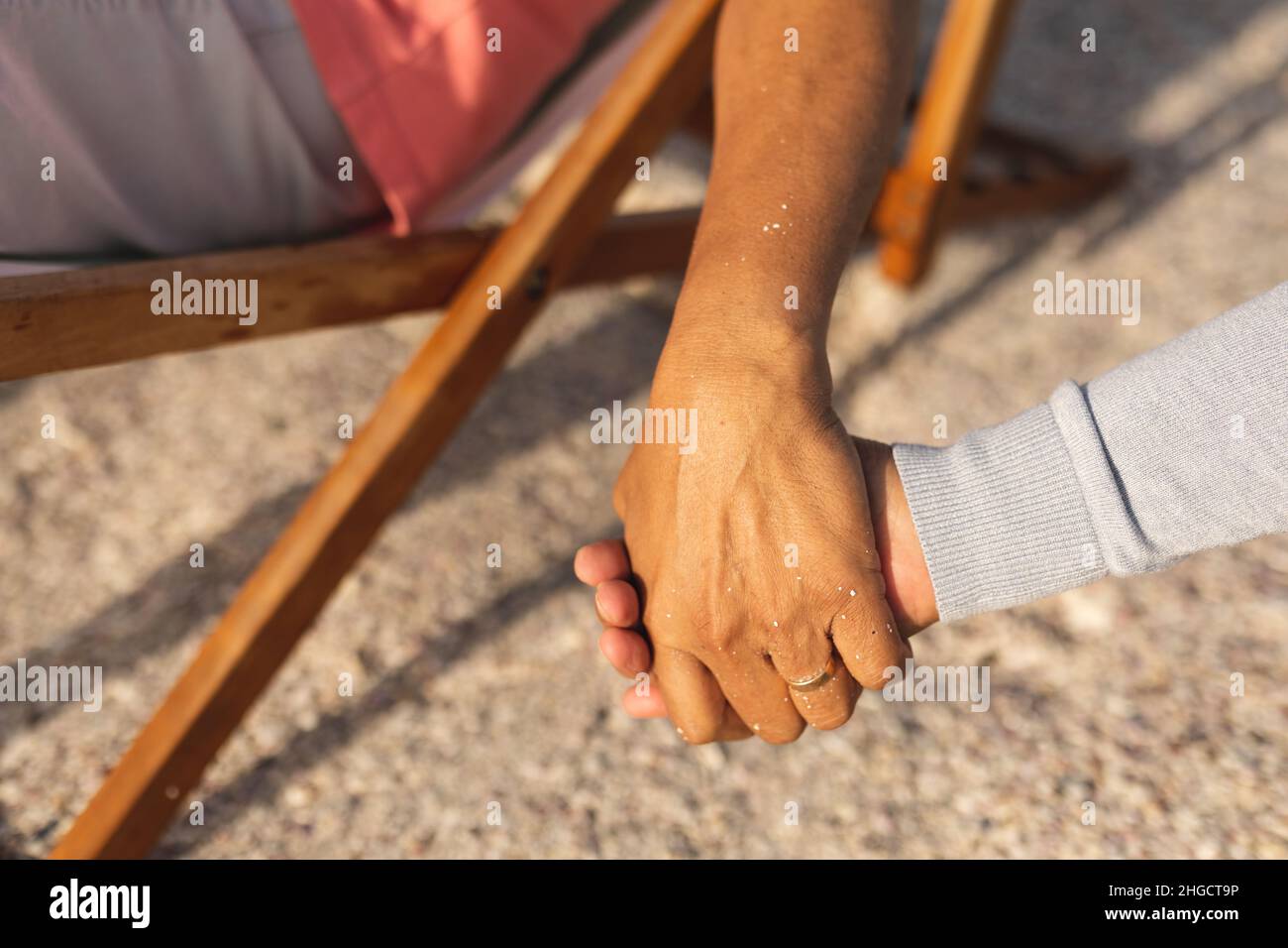 Beschnittenes Bild eines mehrrassischen Seniorenpaares, das sich die Hände hält, während es am Strand in den Ruhestand geht Stockfoto