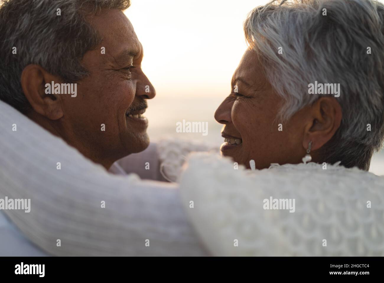 Seitenansicht der liebevollen, neuvermählten, multirassischen älteren Braut und des Bräutigams, die sich gegenseitig angucken Stockfoto