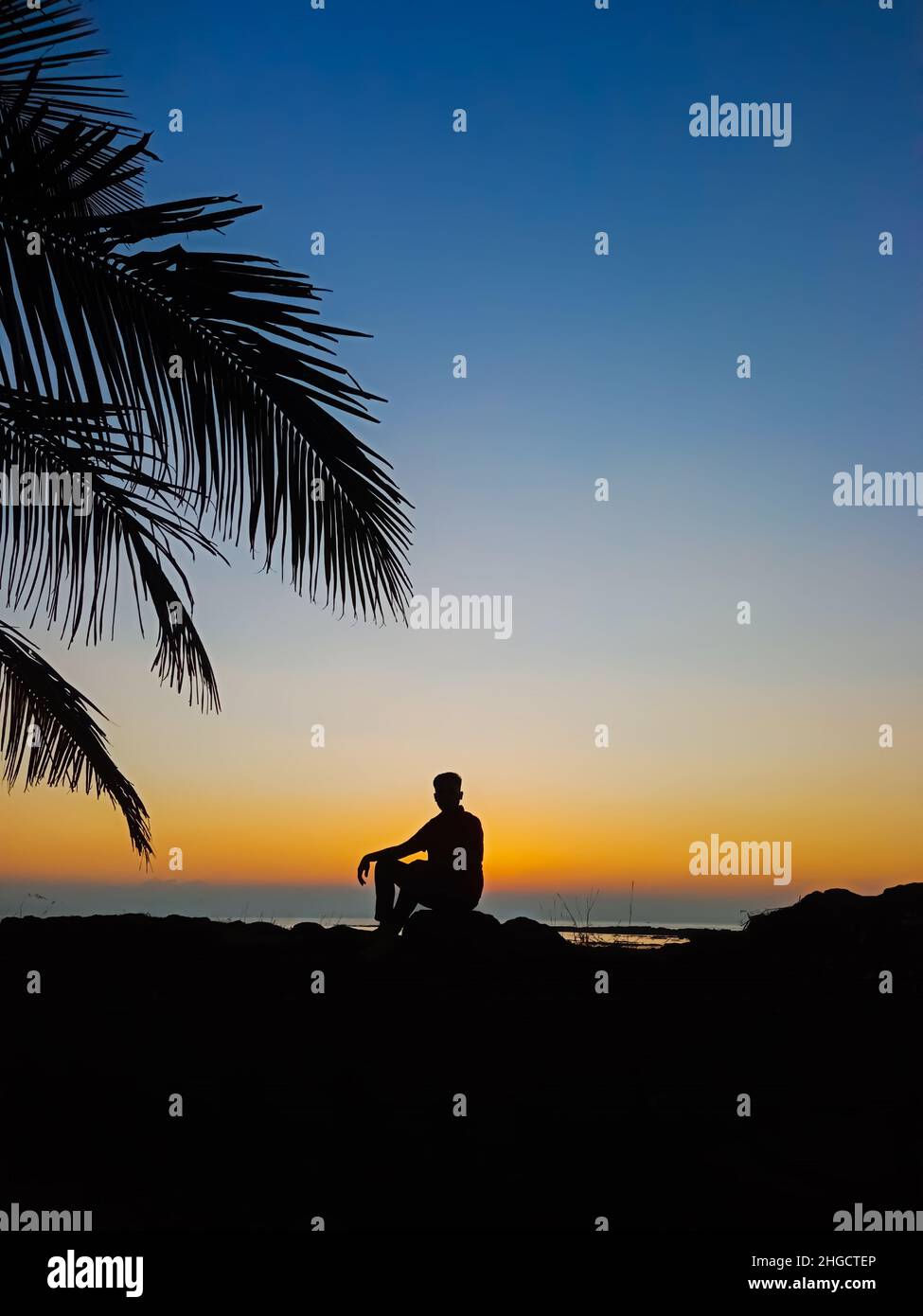 Trauriger Mann, Der Auf Dem Felsen Am Strand Sitzt Stockfoto
