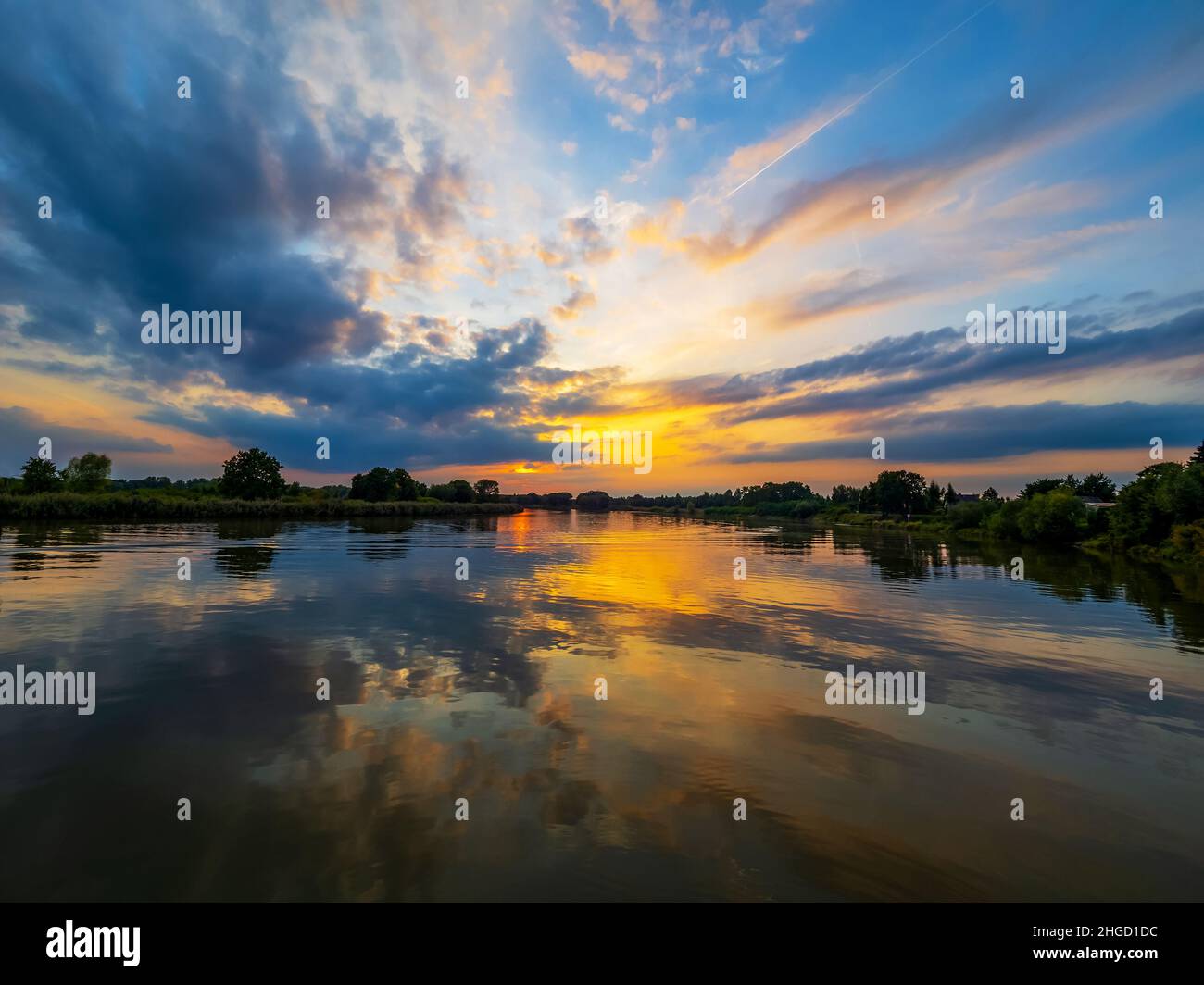 Abendhimmel mit dramatischen Wolken über dem Fluss. Dramatischer Sonnenuntergang in Wolken und Fluss. Naturlandschaft, Reflexion, blauer wolkig Himmel und orange Sonnenlig Stockfoto