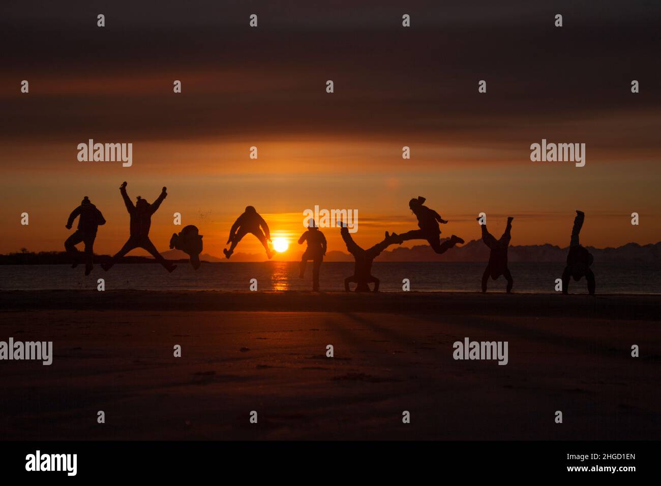 Leute, die Spaß haben, und machen Akrobatik in den Sonnenuntergang am Strand auf den Lofoten Inseln, Norwegen Stockfoto