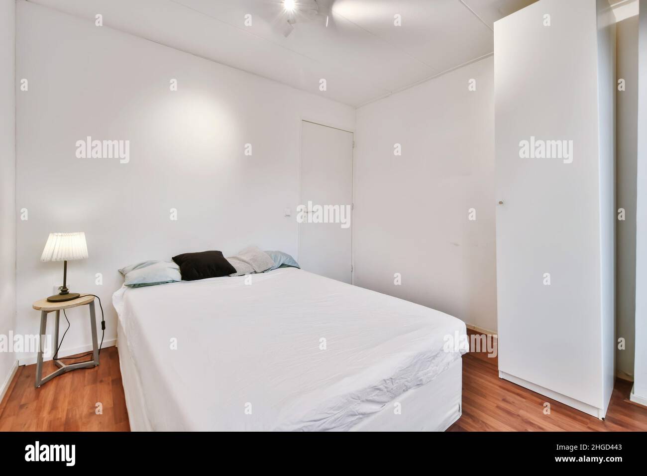 Minimalistisches Schlafzimmer mit einem schneeweißen Bett und einer Lampe auf dem Nachttisch Stockfoto