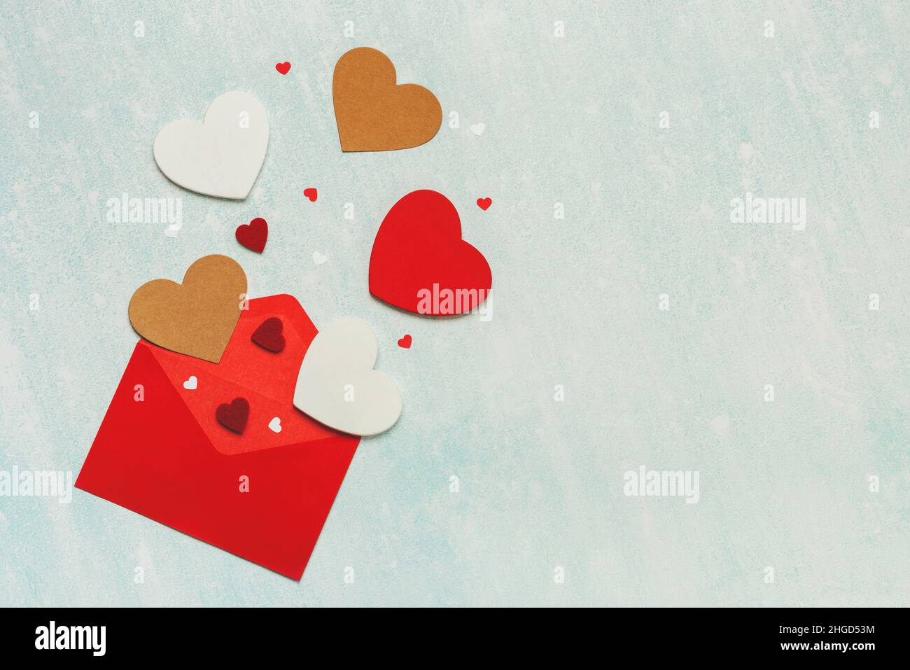 Draufsicht auf roten Umschlag und Herzen mit Kopierraum auf blauem Hintergrund. Konzept für die Valentinstag-Feier Stockfoto