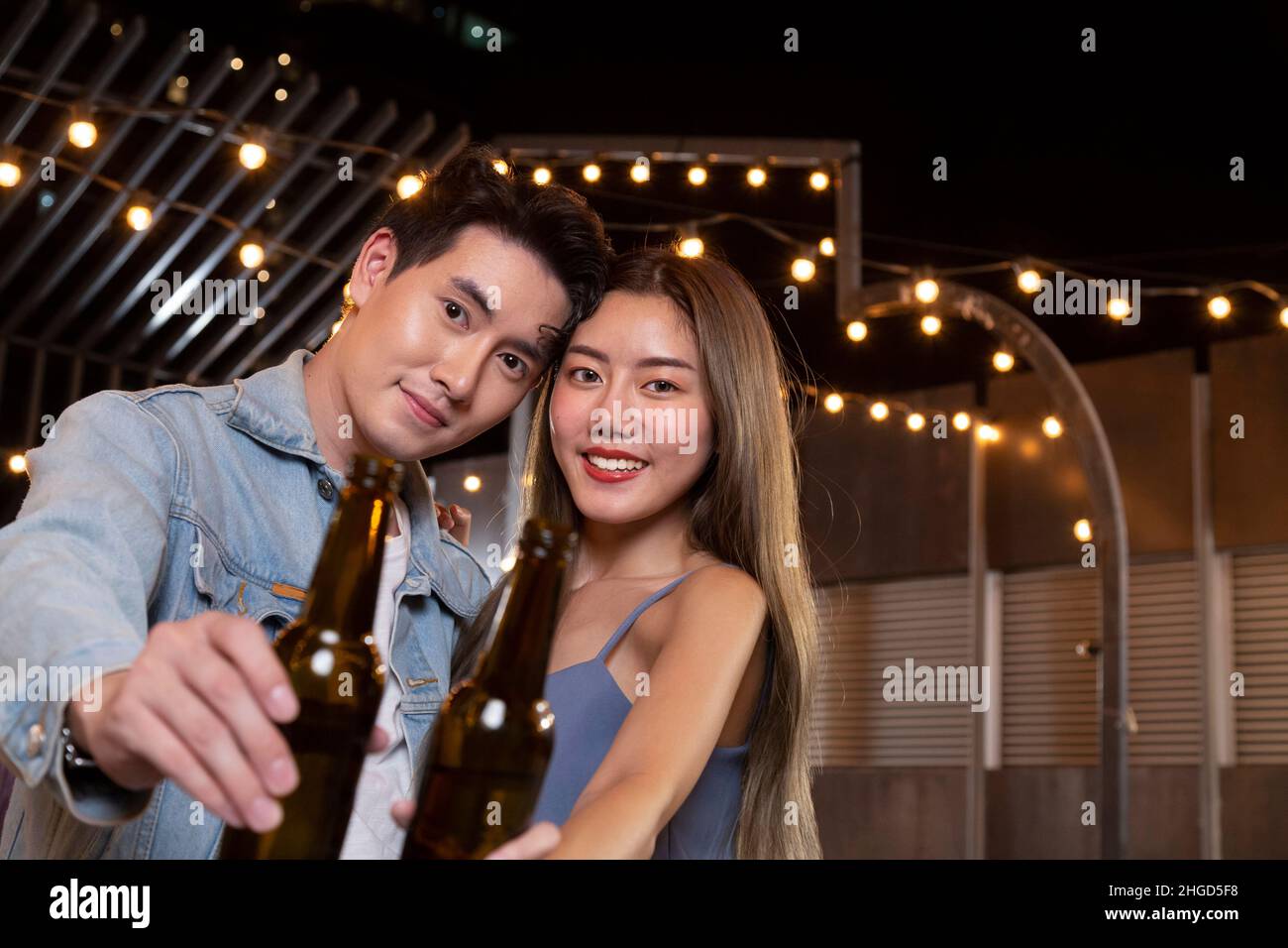 Glücklich asiatische Teenager Paar Mann und Frau verliebt Bier Alkohol trinken und Toasting Flasche in der Feier Partei. Junge glückliche Paar Liebe und romantisch Stockfoto