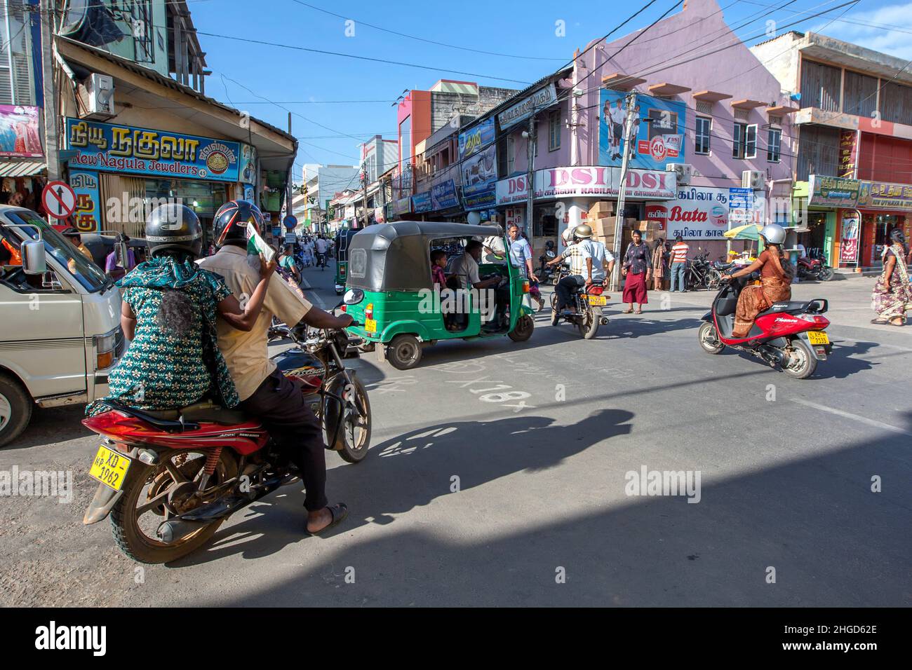 Ein Tuk-Tuk, Motorräder und Fußgänger überqueren eine stark befahrene Straßenkreuzung neben dem Grand Bazar in Jaffna im Norden Sri Lankas. Stockfoto