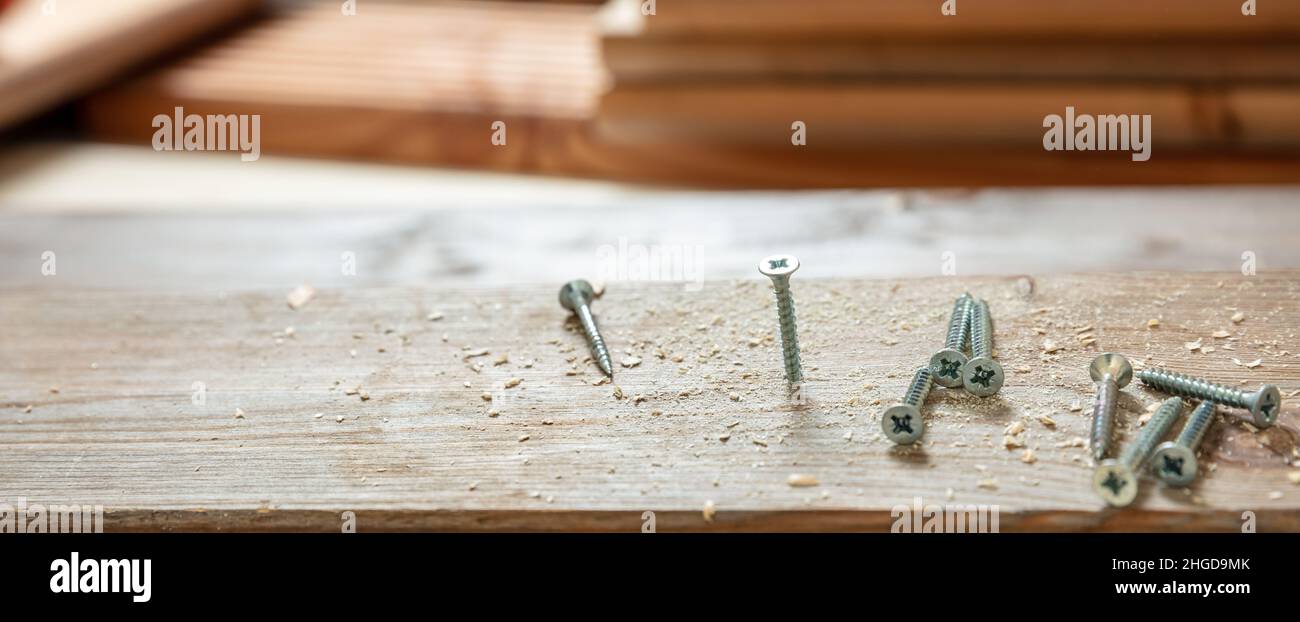 Holzschraube auf Holzbrett, Tischlerwerkstattbank, Nahaufnahme. DIY, Hausreparatur und Reparatur. Stockfoto