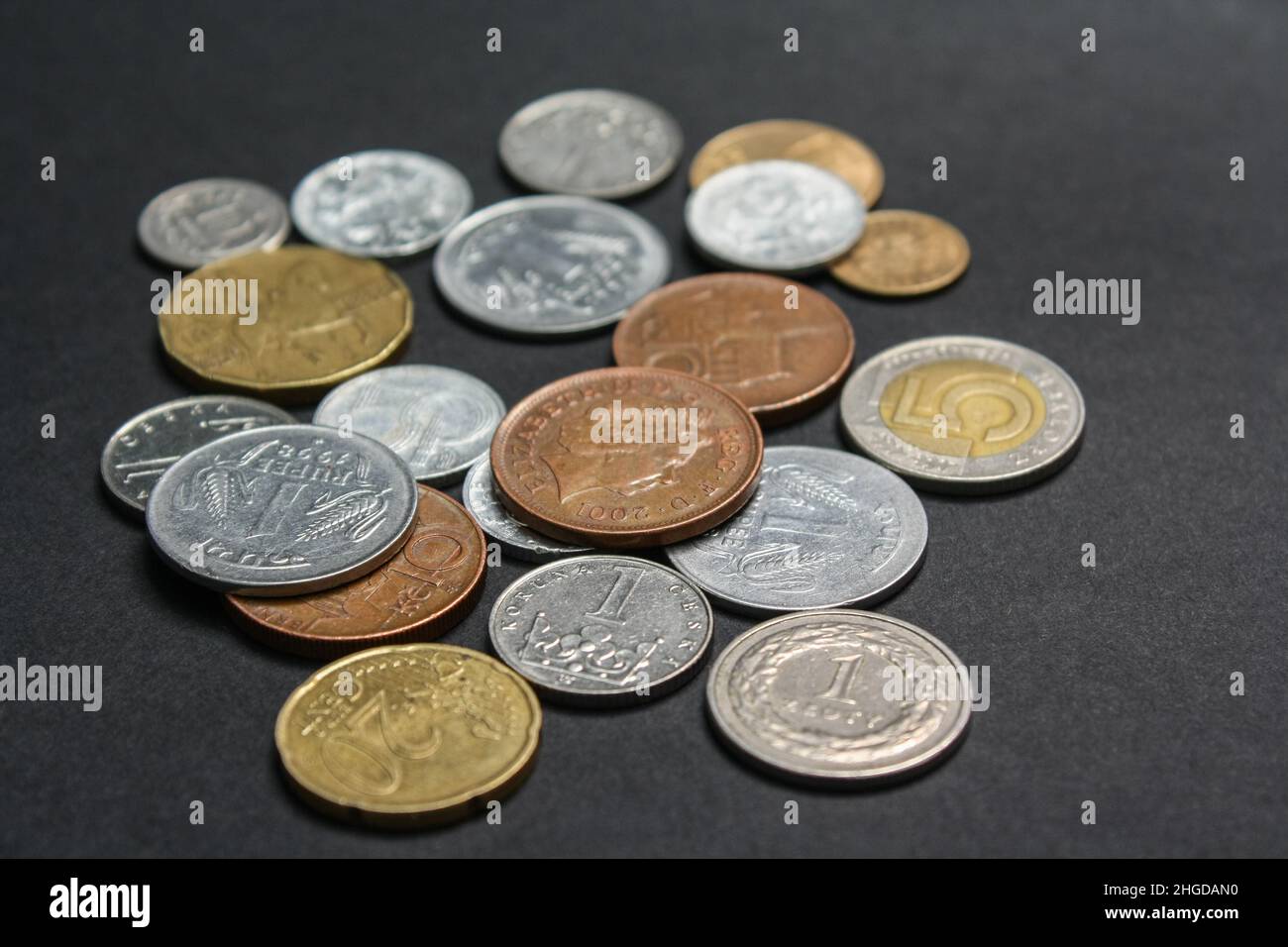 Münzen verschiedener Länder. Eine Streuung von Münzen auf schwarzem Hintergrund. Geringe Schärfentiefe Stockfoto