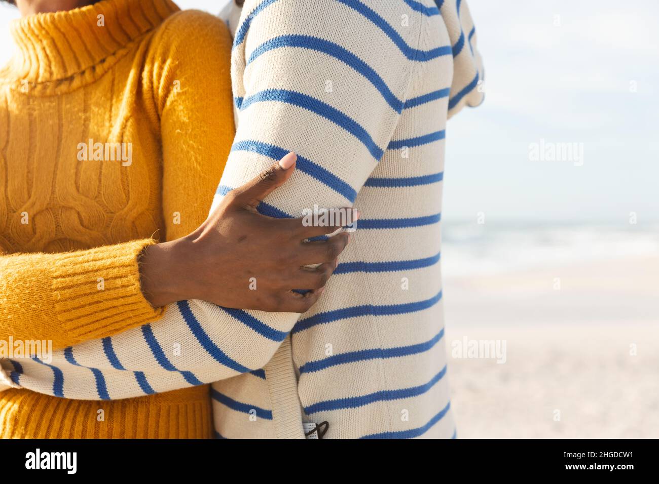 Mittelteil des multirassischen Paares, das sich am sonnigen Tag am Strand umarmt Stockfoto