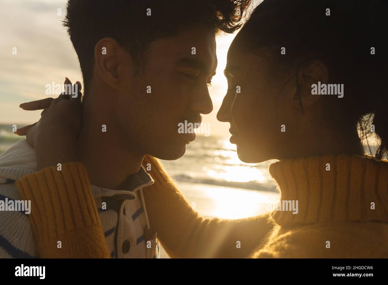 Romantisches multirassisches Paar, das sich während des Sonnenuntergangs von Angesicht zu Angesicht anschaut Stockfoto