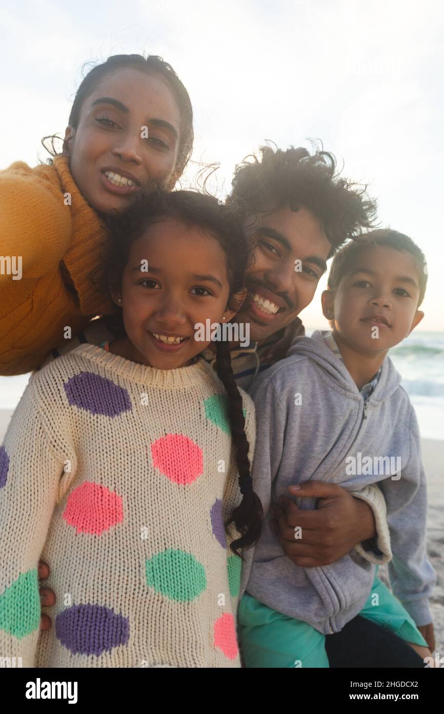 Porträt einer glücklichen multirassischen Familie, die Selfie macht und den Sonnenuntergang am Strand gegen den Himmel genießt Stockfoto