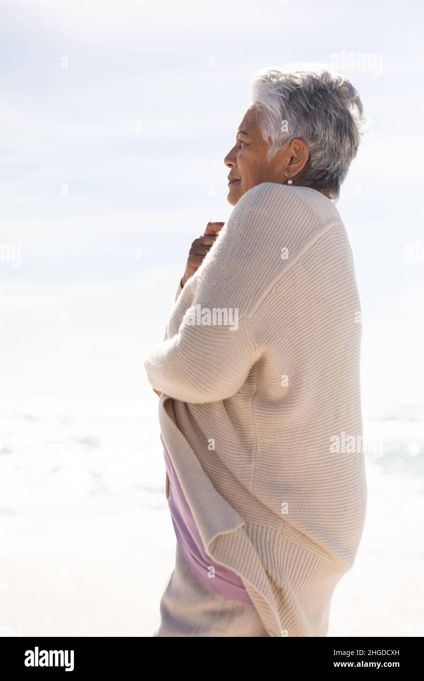 Seitenansicht einer älteren Frau mit kurzen weißen Haaren, die am Strand an sonnigen Tagen mit einem Achselzucken zuckte Stockfoto