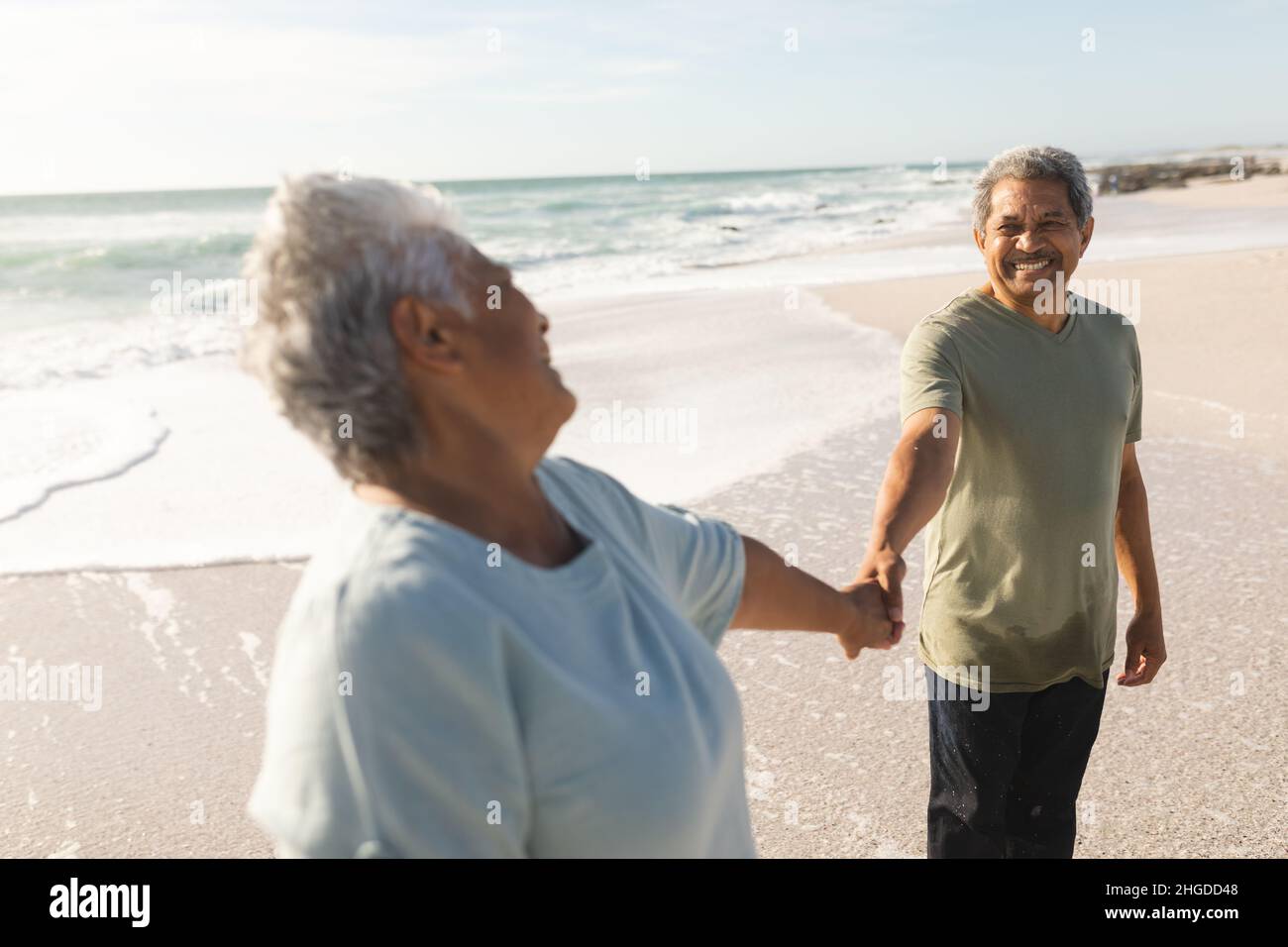 Glückliches, pensionierte, mehrrassisches Senioren-Paar, das sich an Land ansah und die Hände hielt Stockfoto