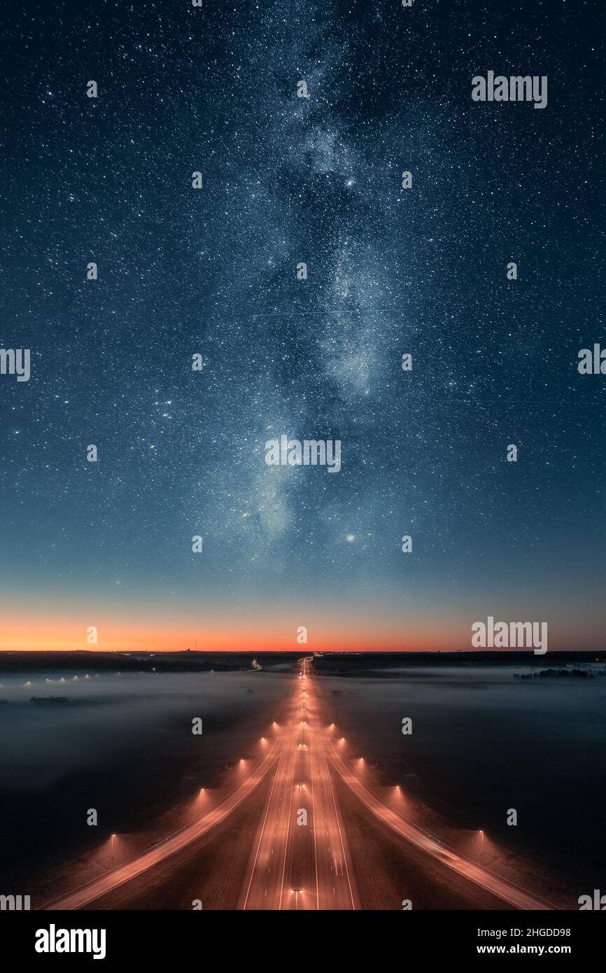 Epische Aussicht auf die Autobahn bei Nacht mit wunderschönen Sternen und Milchstraße am Himmel. Hintergrund für den Transport. Stockfoto